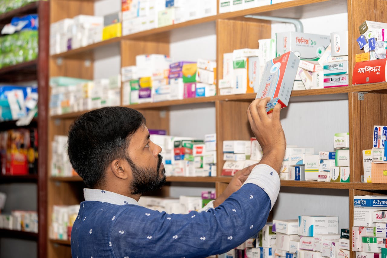 services-04 A pharmacist organizing medication on shelves in a pharmacy in Bangladesh.