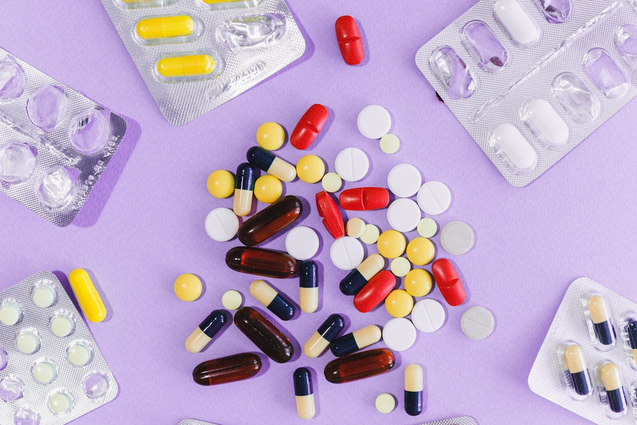 about-us A variety of colorful pills and capsules displayed on a purple background in blister packs.